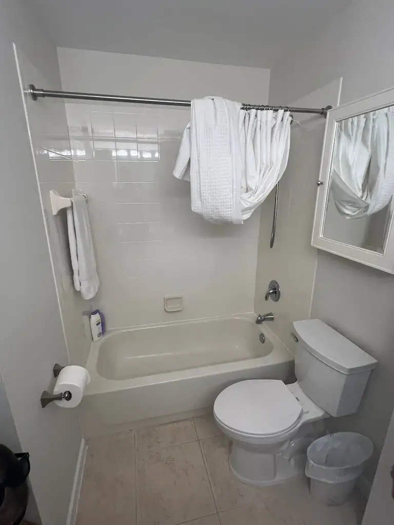 Clean white bathtub with glass shower door and mirror wall.