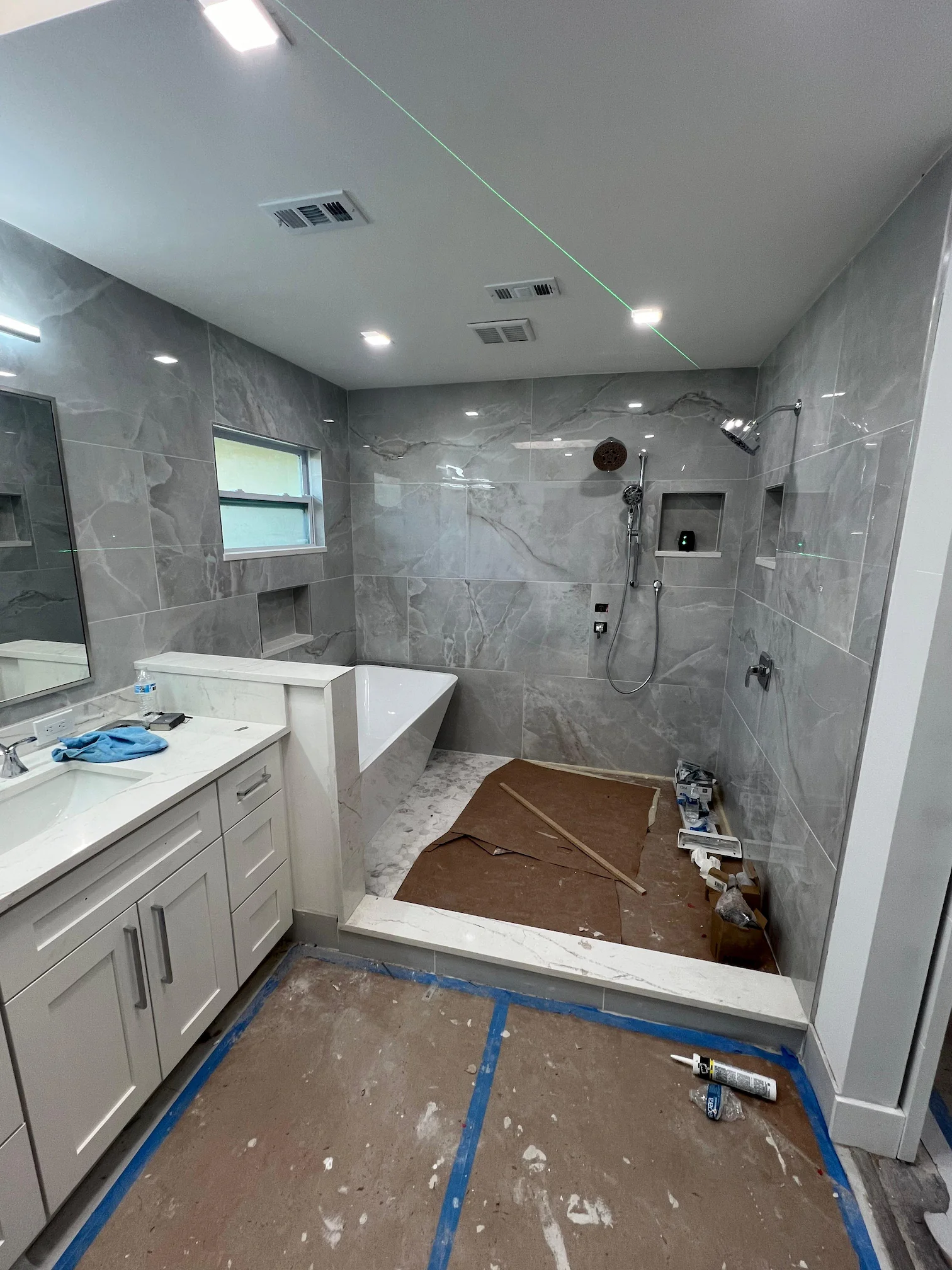 Modern bathroom with crystal glass shower enclosure and marble wall tiles.