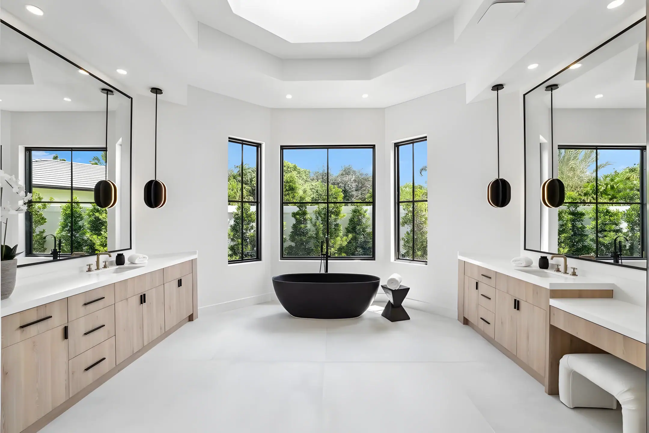 Luxury bathroom with glass mirror vanities and black bathtub centerpiece.