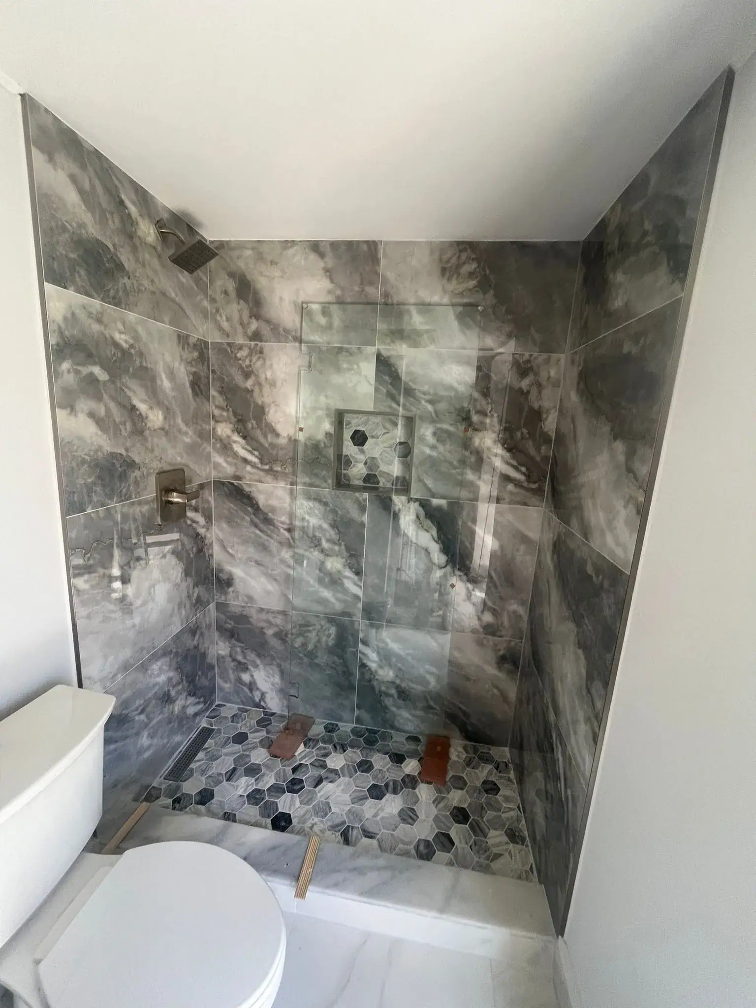 Elegant marble shower with glass wall, contemporary bathroom design, high-quality glass and tile work.