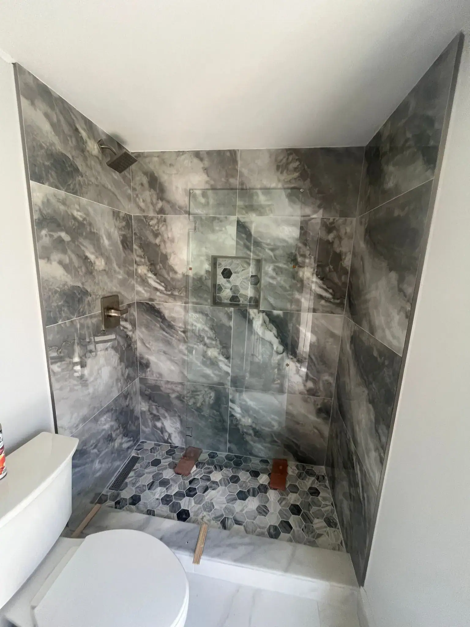 High-quality glass shower with marble and mosaic tiles, custom mirrors, and modern fixtures for luxury bathrooms.