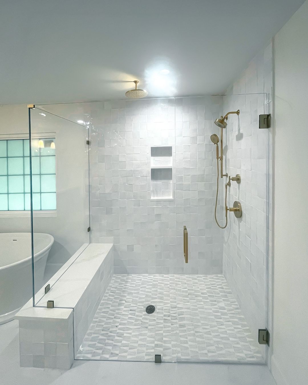 High-quality glass shower door with stylish brass hardware, white tiled walls, and elegant bathroom design.
