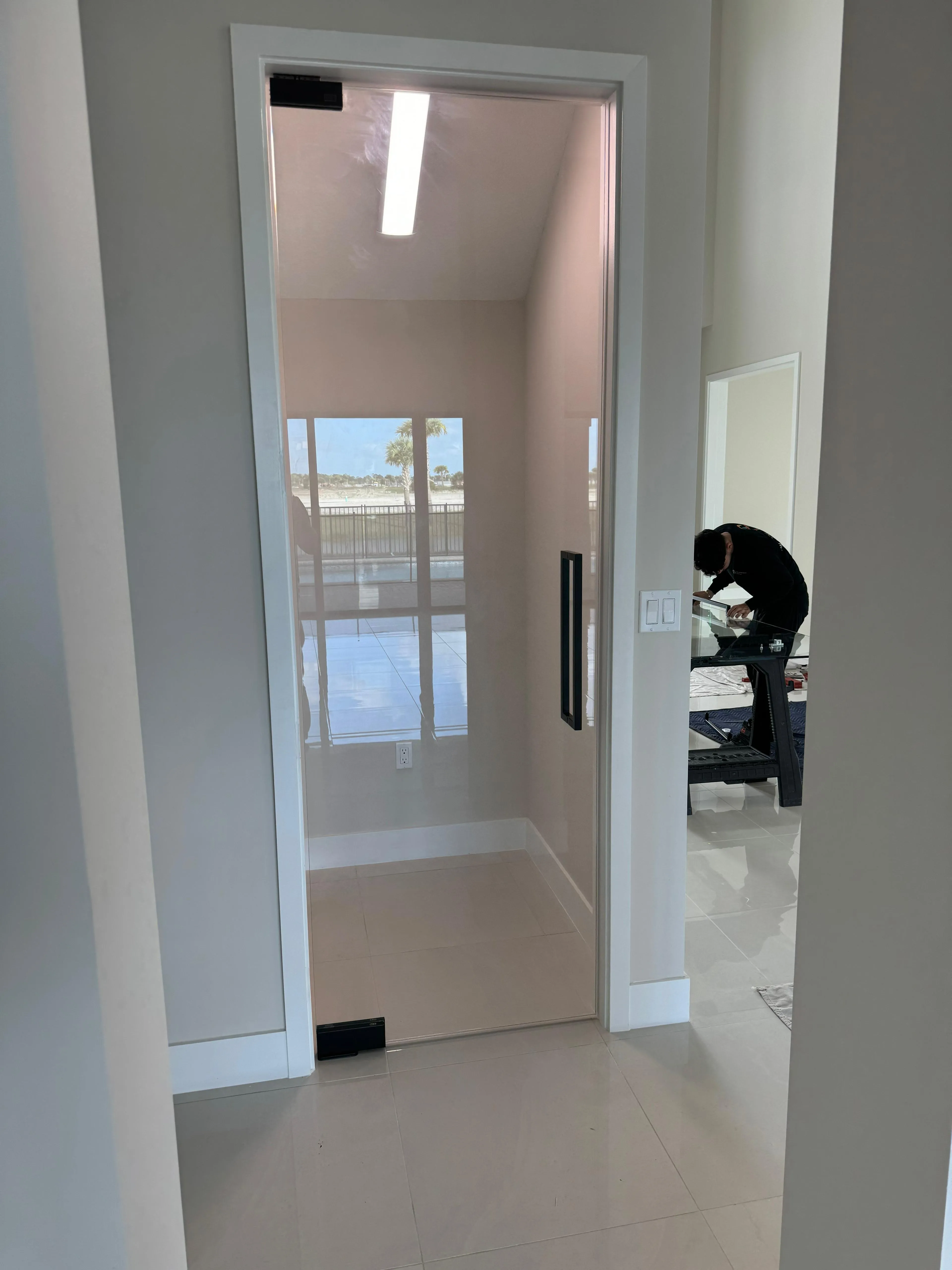 Reflective glass elevator door with sleek black handle, located in a contemporary home or office space.