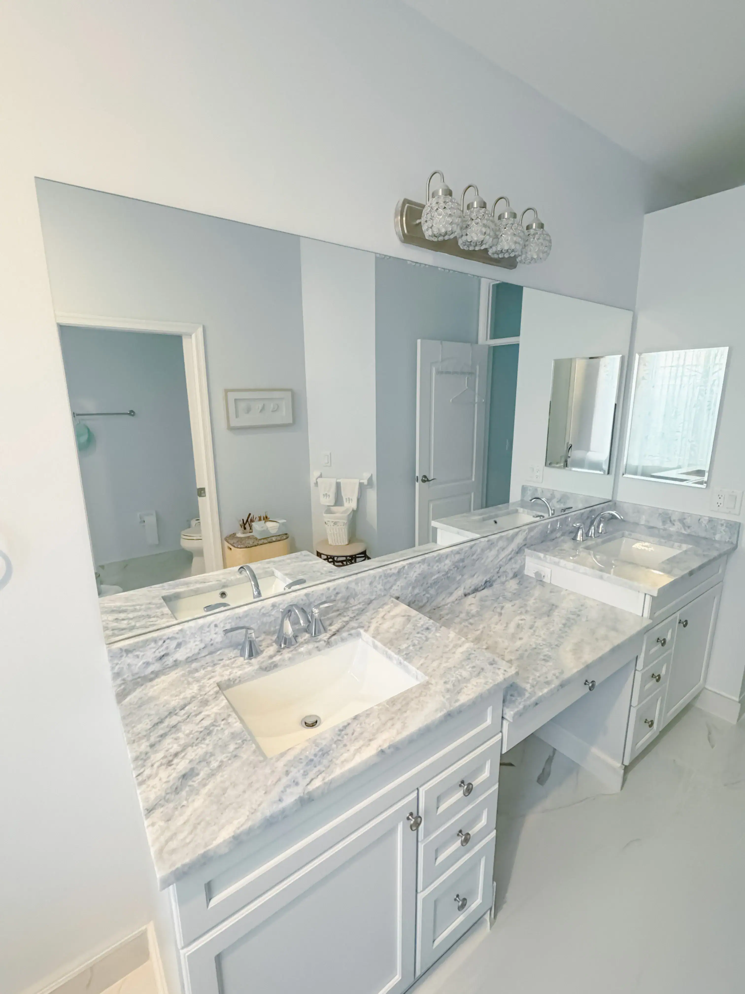 Alt text: Double bathroom vanity with white marble countertops, modern sinks, and large mirror, featuring high-quality glass and mirror services.