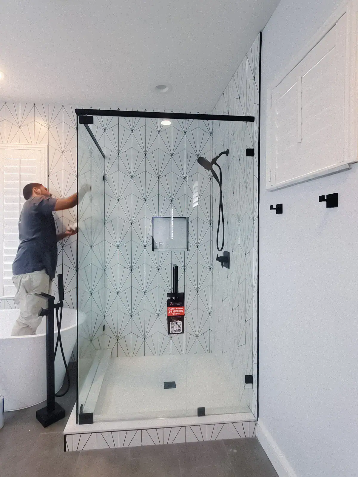 Highly reflective glass shower door with black hardware accents.