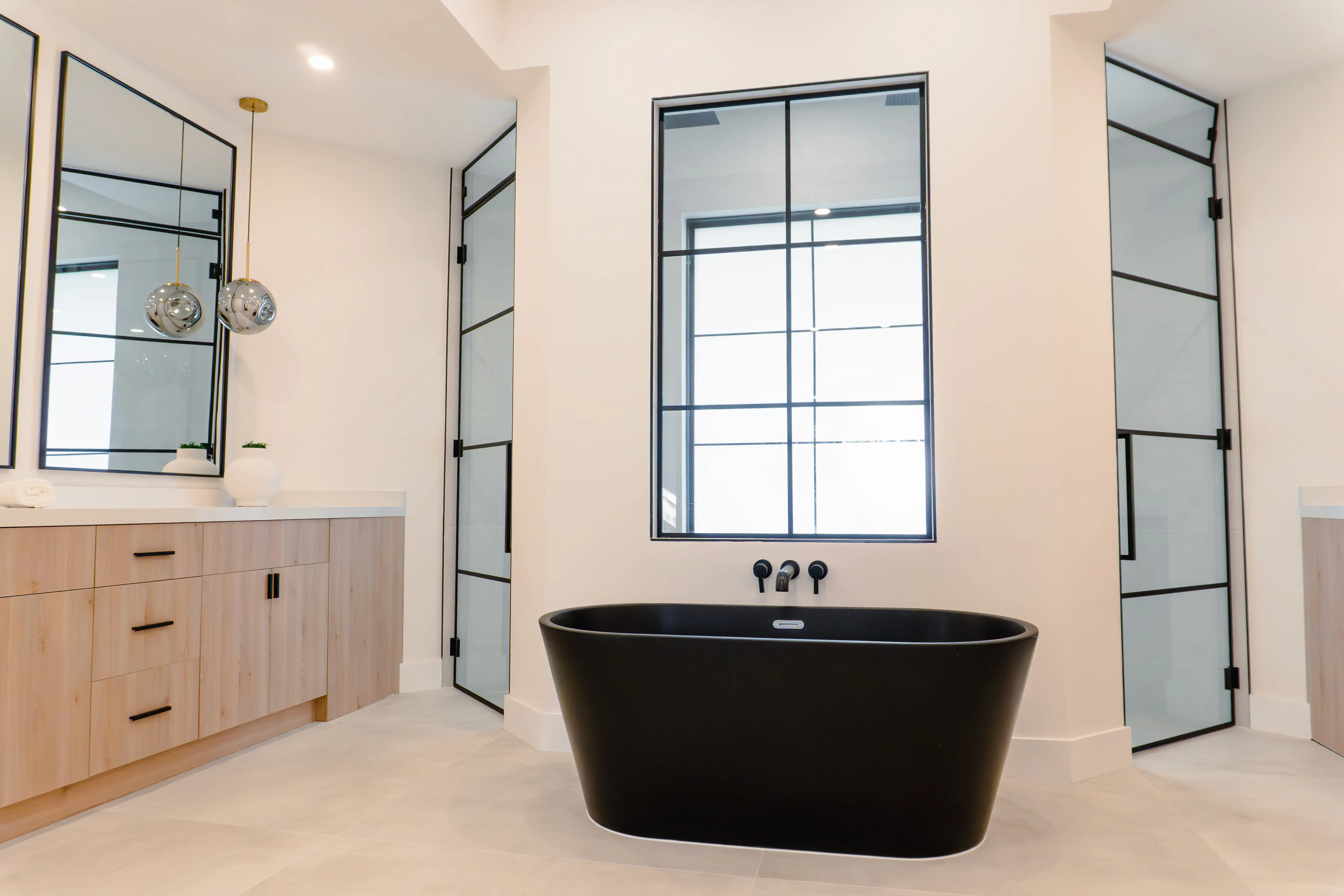 Stylish black freestanding bathtub in a contemporary bathroom featuring glass shower enclosures and minimalist décor.
