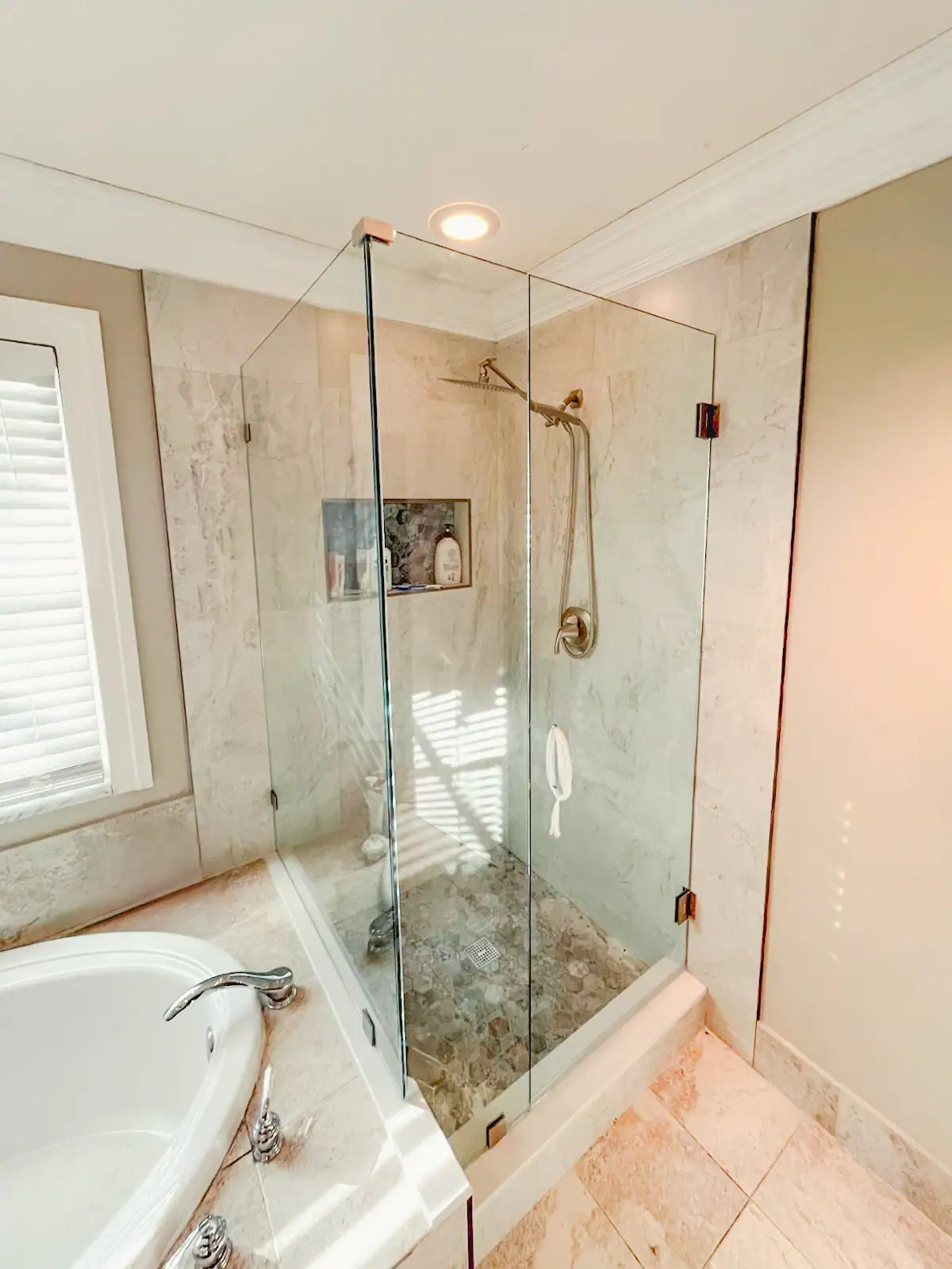 Clear glass bathroom shower door with brass hardware and stone tile interior for elegant showers.