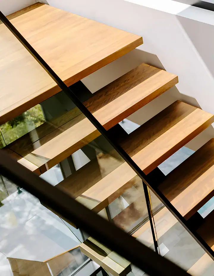 Staircase featuring glass risers and wooden treads for elegant interior design.