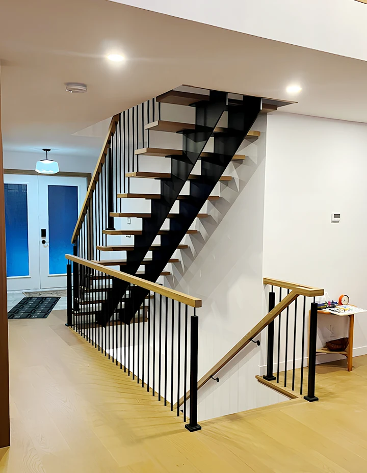 Modern glass staircase with sleek black and wood accents, stylishly enhances home interior design.