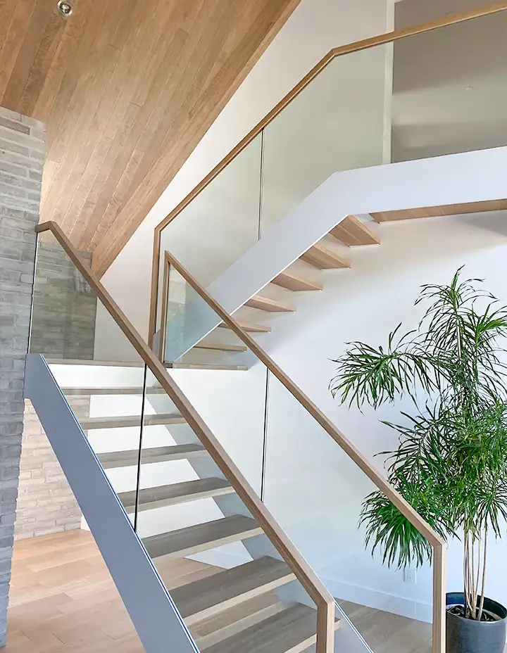 Bright glass staircase with wooden handrails and sleek design.