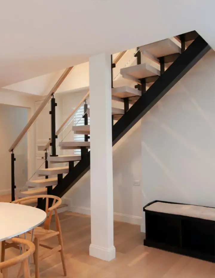 Elegant glass and metal staircase with wooden accents in modern home interior.