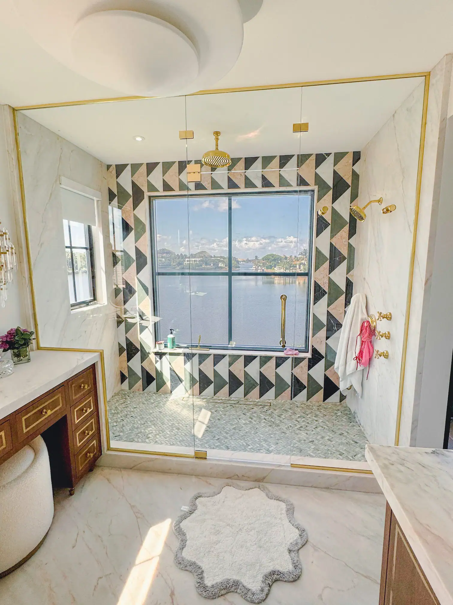 Beautiful glass shower with river scenery, featuring gold fixtures and decorative tile work.
