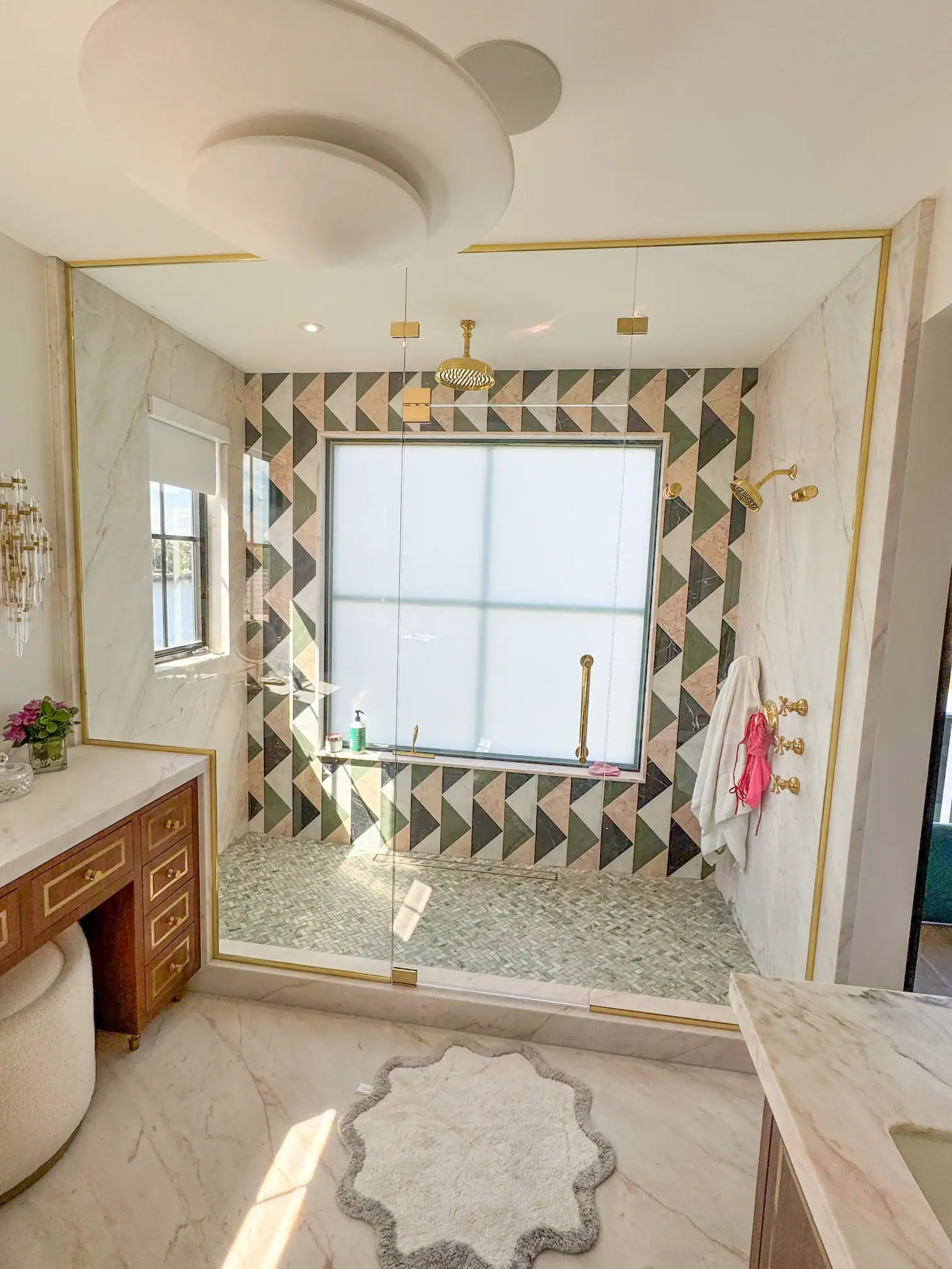 Luxurious marble and glass bathroom shower with gold accents, modern design, and natural light.