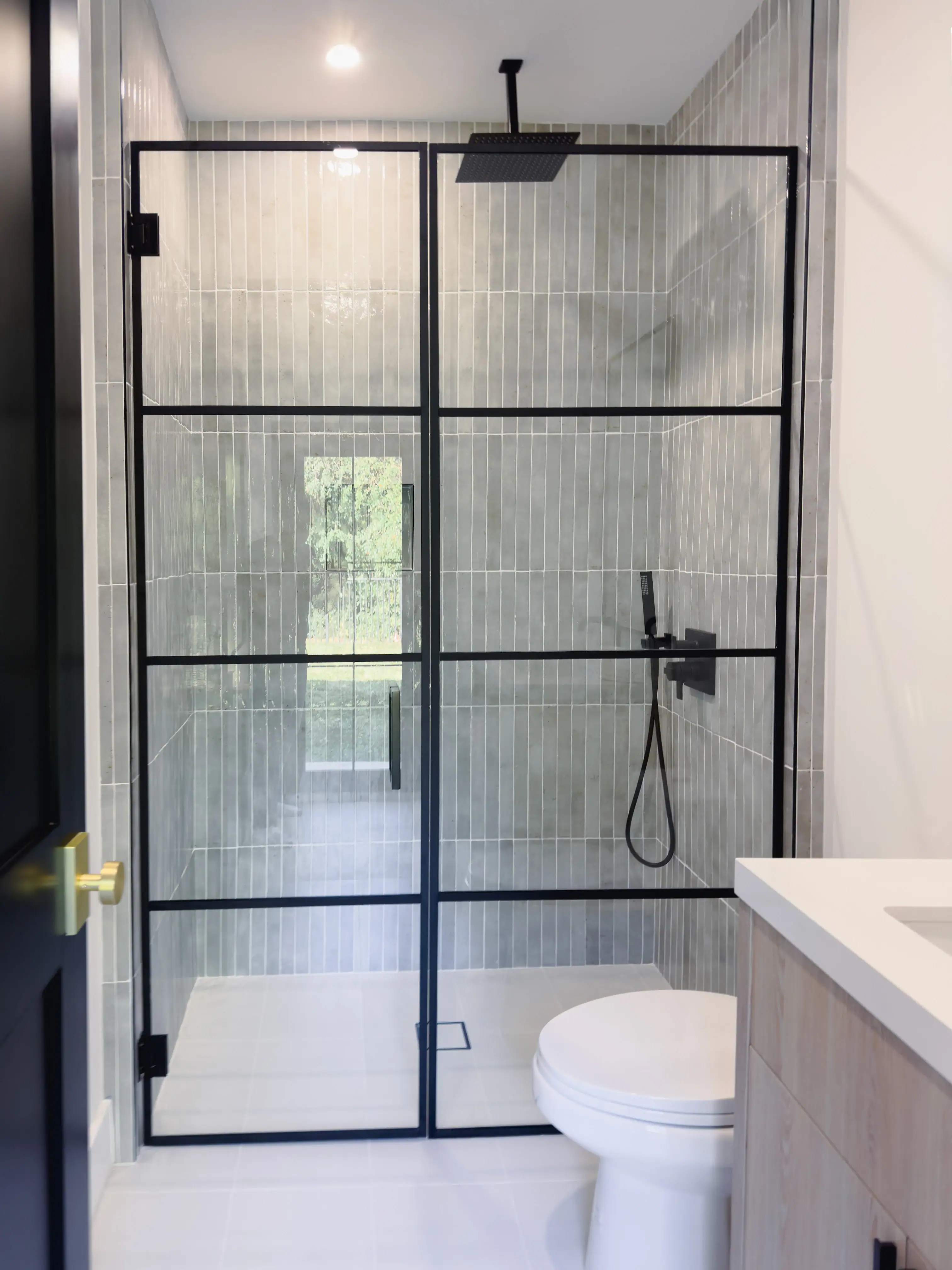 High-quality glass shower door with black metal frame in contemporary bathroom.