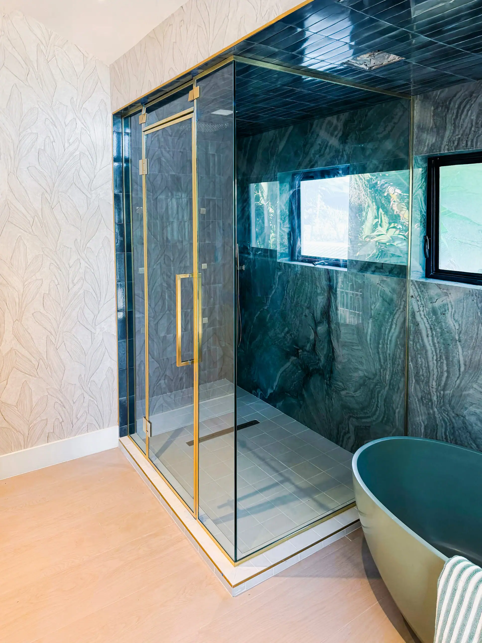 Stylish glass shower with gold hardware, modern design, and elegant mirrors enhances bathroom decor.