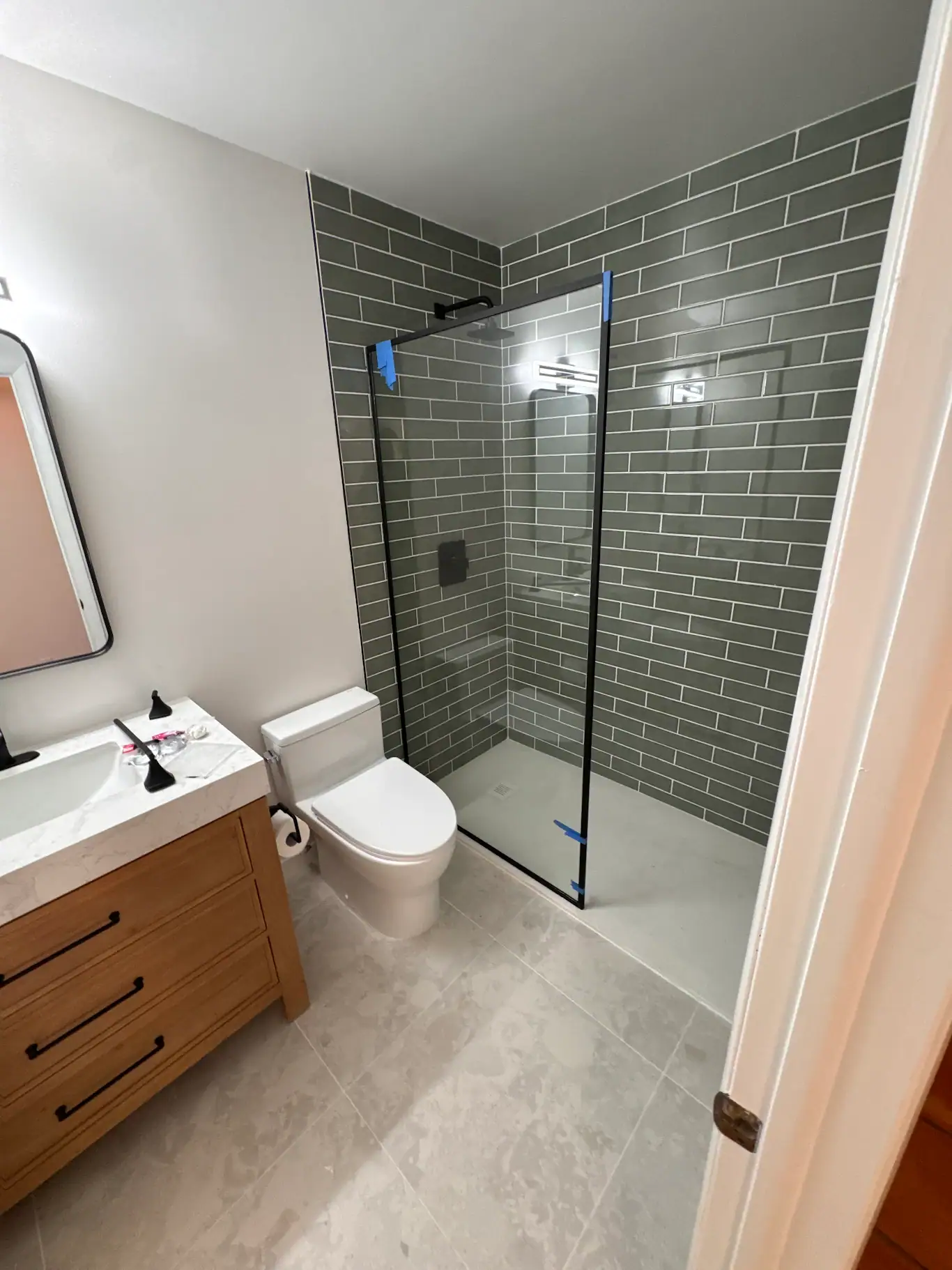 High-quality glass shower enclosure for bathroom remodels. Modern design with sleek black trim, gray subway tiles.