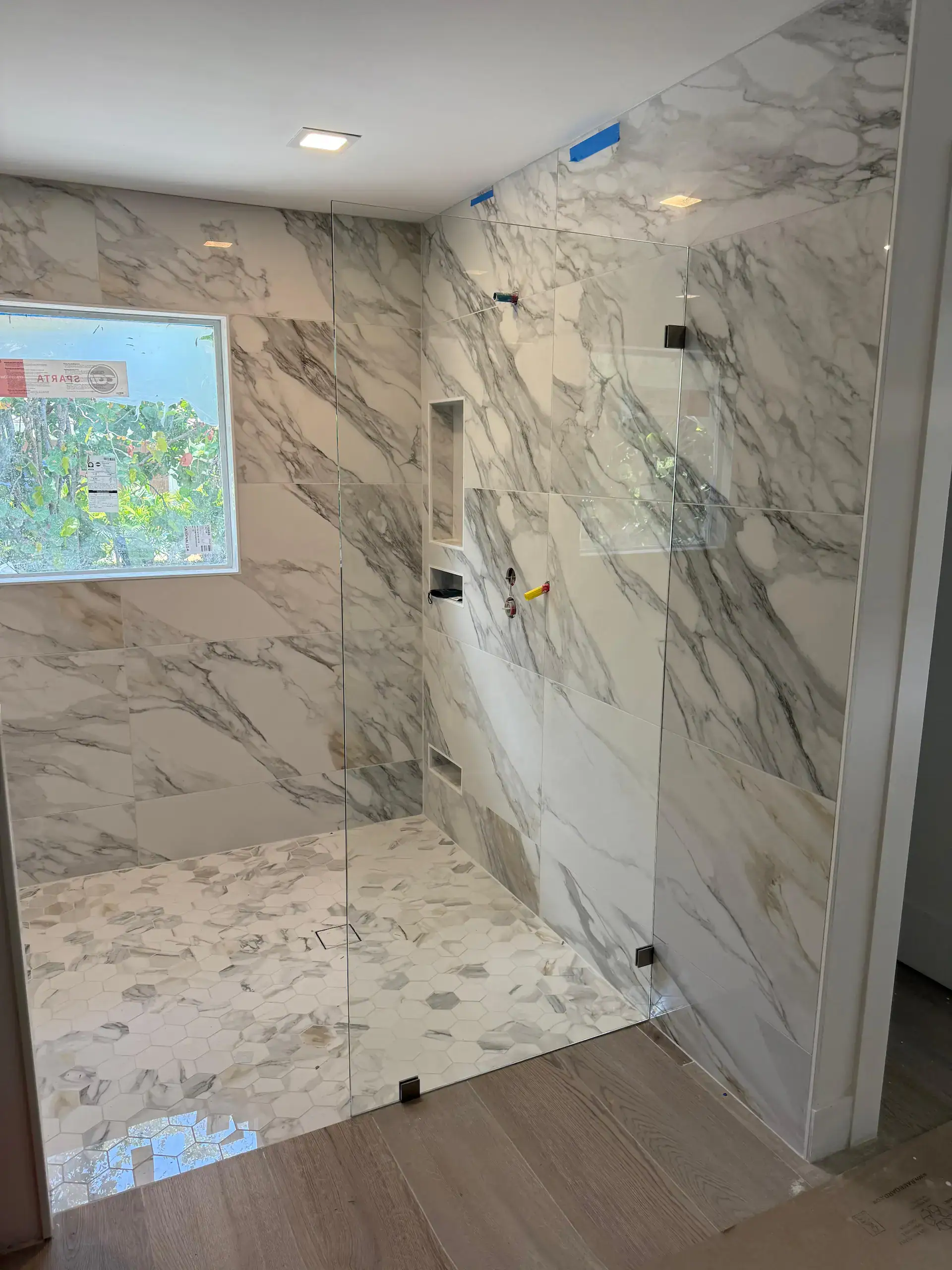 High-quality glass shower enclosure with marble walls and flooring, modern design, and sleek clear glass panels.