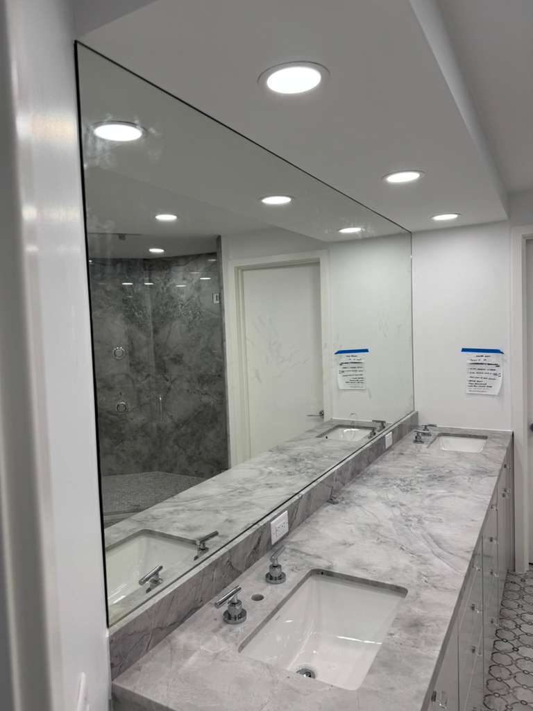Large decorative mirror in bathroom with marble countertop and double sinks.