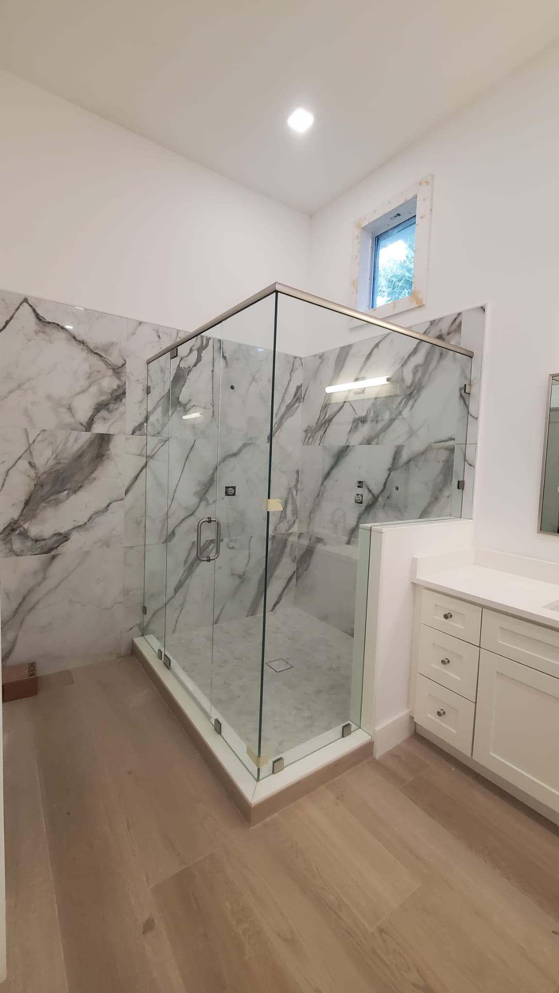 Custom glass shower enclosure featuring clear frameless glass and marble walls for luxury bathrooms.