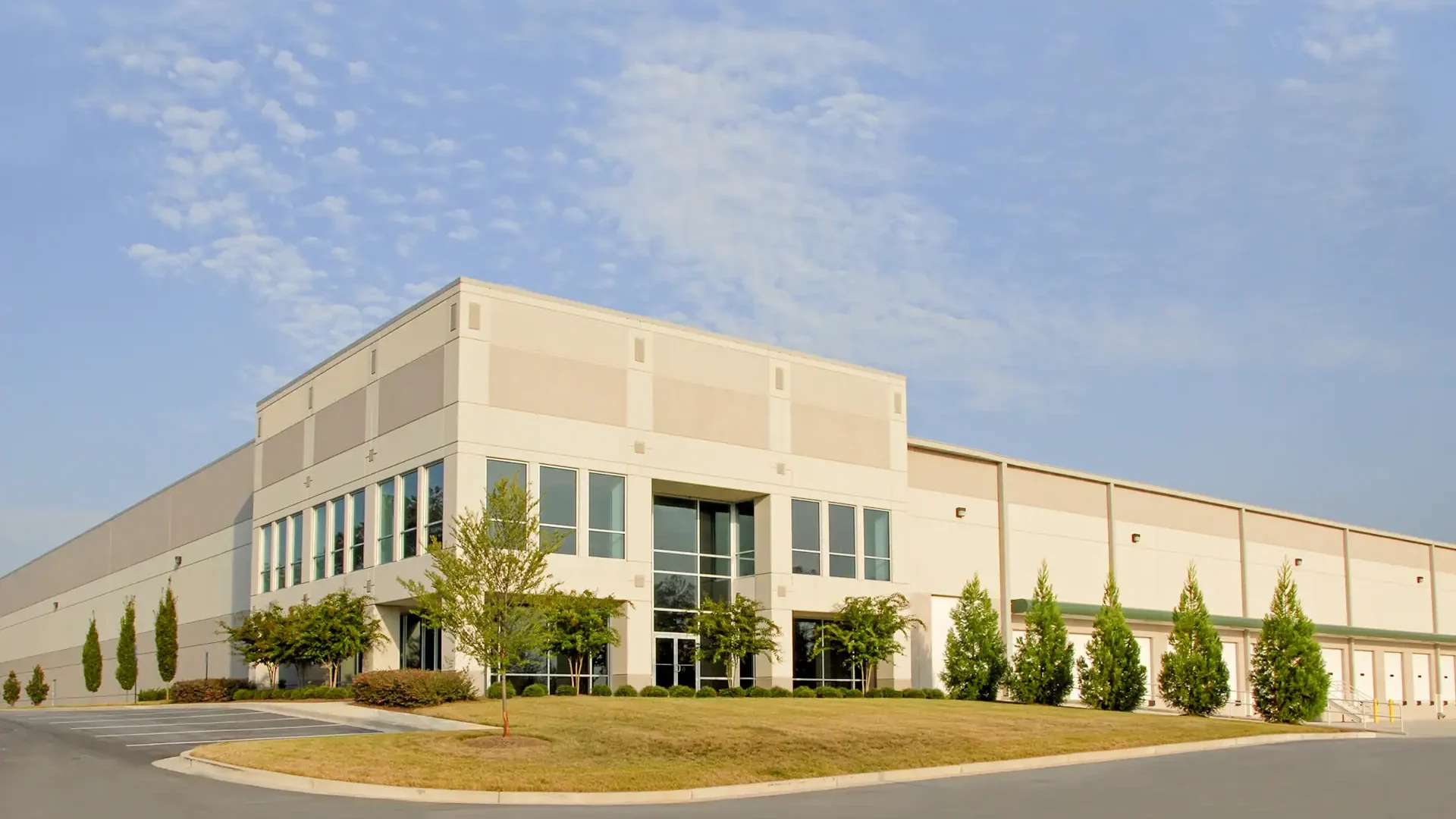 Bright, modern commercial building with lush landscaping, showcasing professional glass and mirror solutions.