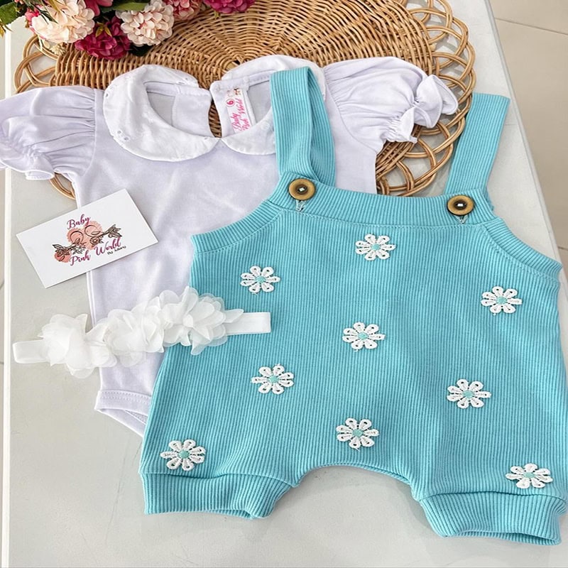 Ropa de bebé blanca y azul con detalles florales, perfecta para bebés y niñas pequeñas.