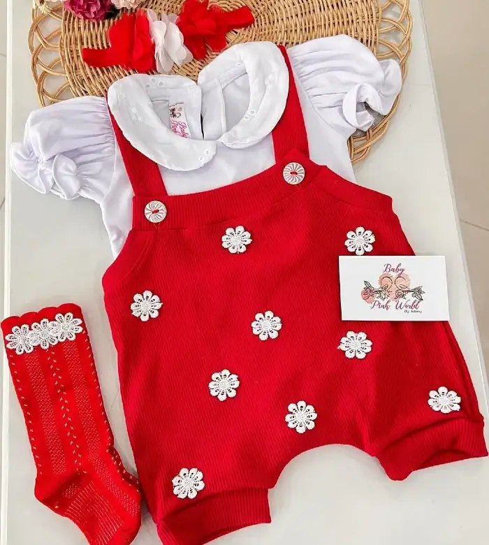 Ropa de bebé rosa y roja con detalles de flores blancas, diadema a juego y medias bordadas perfectas para niña pequeña.
