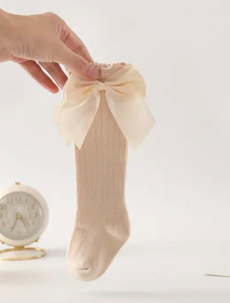 Medias de bebé rosa con lazo de tela suave y delicada para niña. Perfectas para ocasiones especiales o diario.