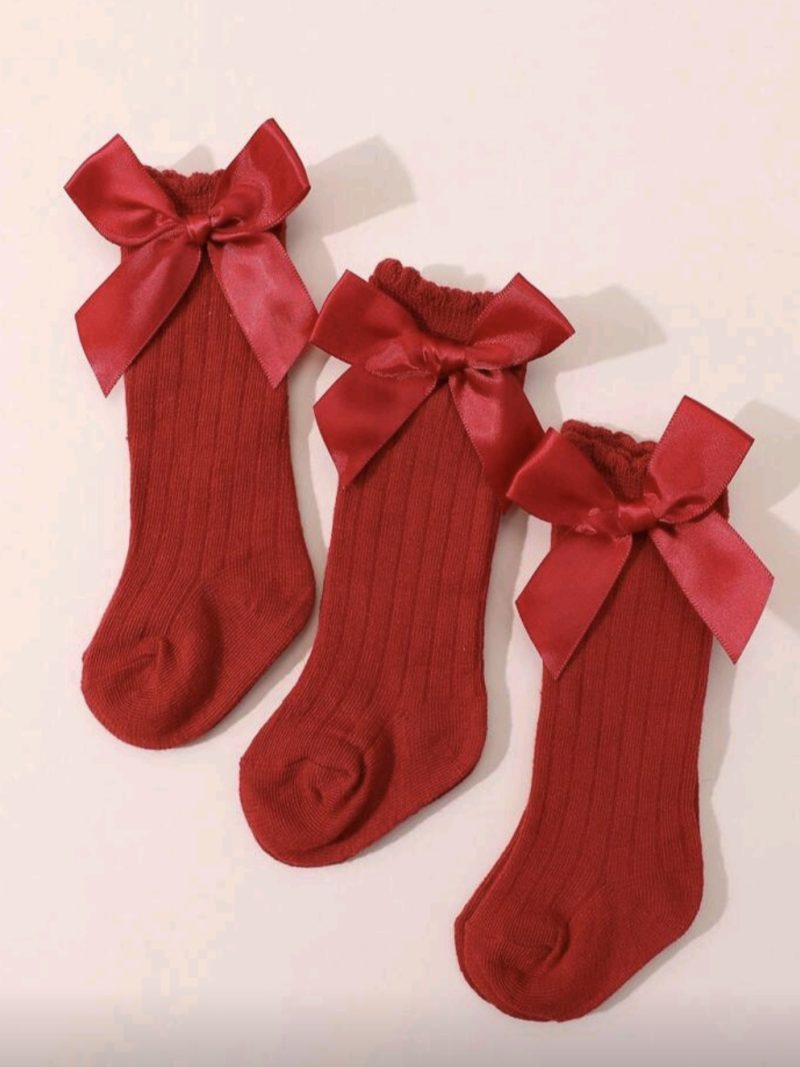 Medias infantiles con lazo de satén rojo para niñas, ideal para ocasiones especiales.